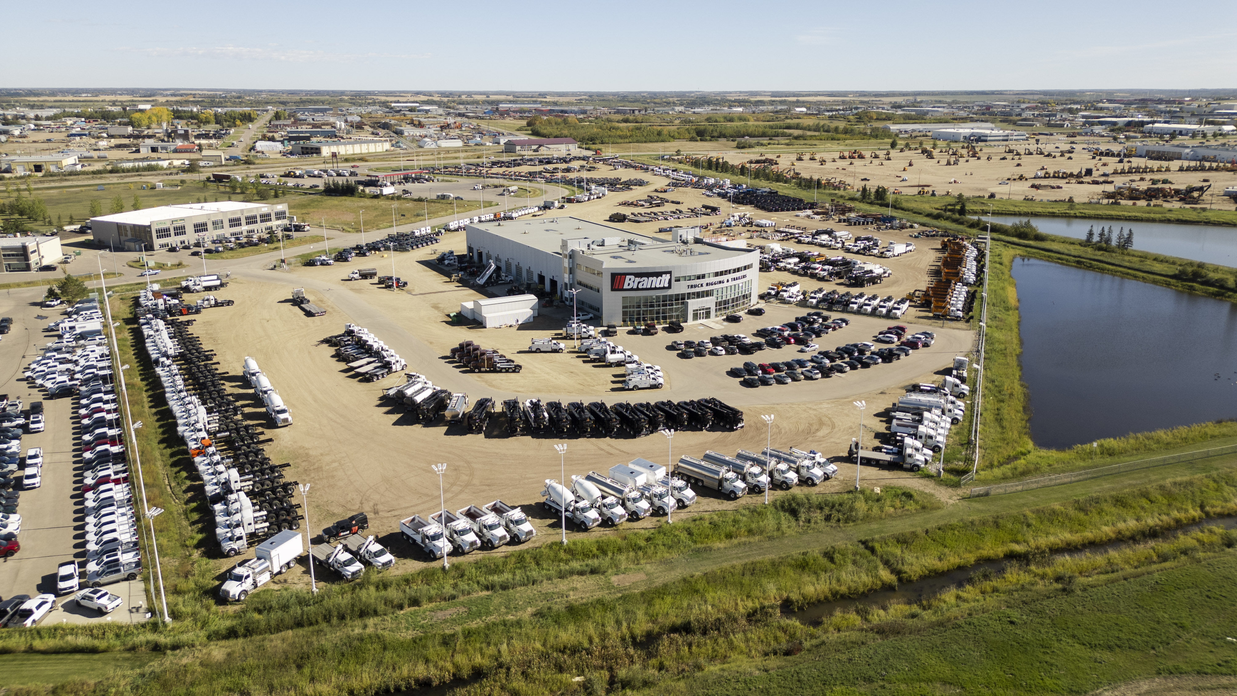 Aerial view of a Brandt dealership showing a large building surrounded by trucks and heavy equipment.